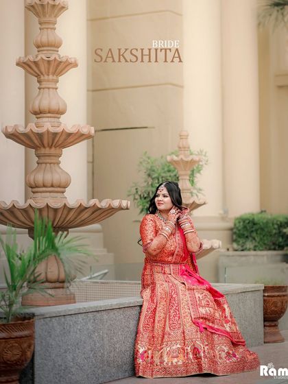 A portrait of the bride seated by a classic three-tiered fountain. The elegant setting complements her traditional attire, creating a regal and beautiful pre-wedding photograph.