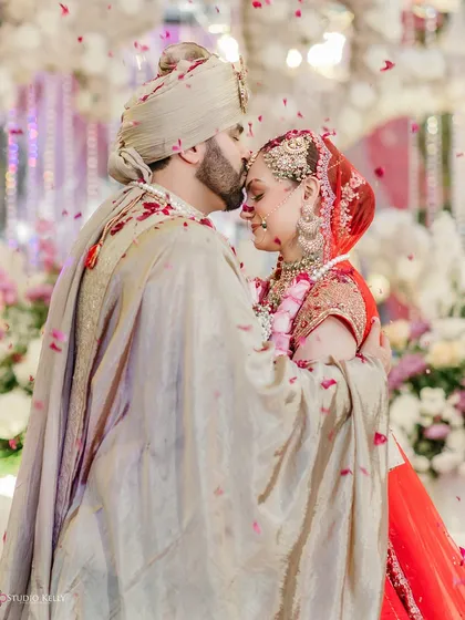 A tender moment as the groom kisses the bride's forehead, their embrace illuminated by the soft glow of the evening, capturing the romance of their wedding day.