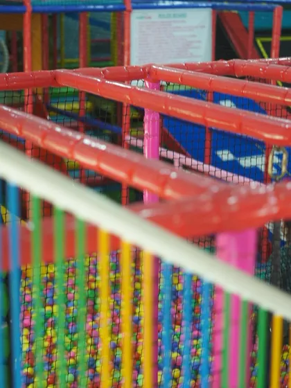 A close-up of our colorful and safe play structures. The bright red bars and netting show the sturdy construction that keeps the fun contained and secure.