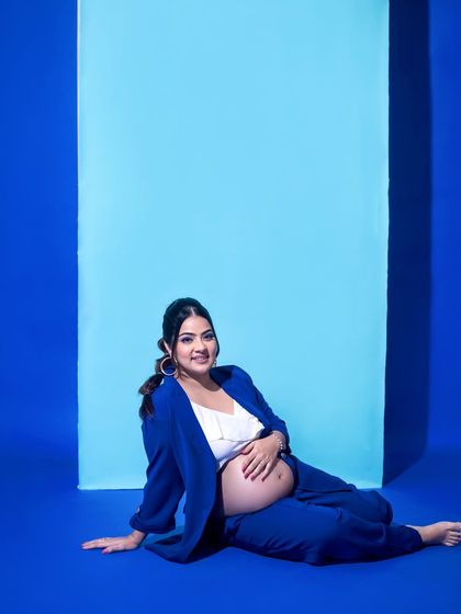 A relaxed, seated pose that is both comfortable and chic, perfect for showcasing a bold and modern maternity outfit.