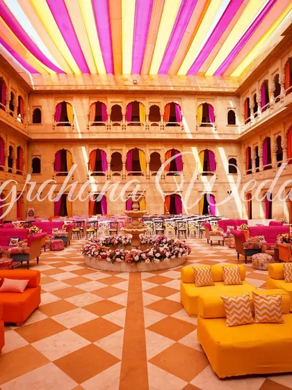 We love playing with color and scale. For this Mehendi in a Jaisalmer palace, we filled the courtyard with vibrant orange and yellow seating under a ceiling of colorful drapes, transforming the historic space into a joyful, modern mela.