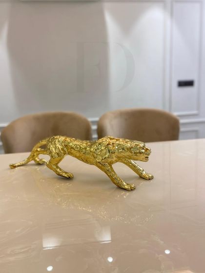 A close-up of a gold-leafed leopard sculpture, one of the many decor items we use to add a touch of personality and opulence to our interior designs.