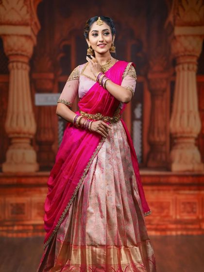 A graceful pose showing the flow of the half saree's dupatta and the intricate design of our peacock-themed vaddanam.