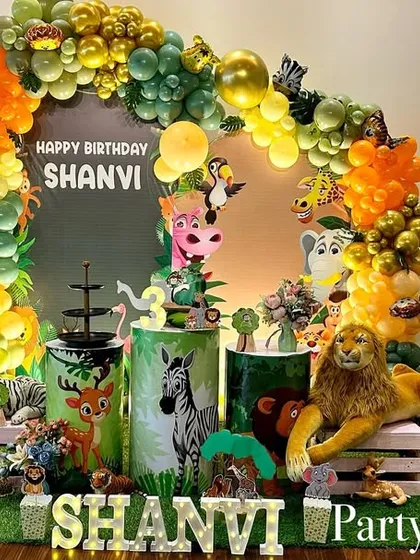 A vibrant jungle animal theme with a focus on cute, plush animals and a colorful balloon arch. The artificial grass floor covering completes the safari look.