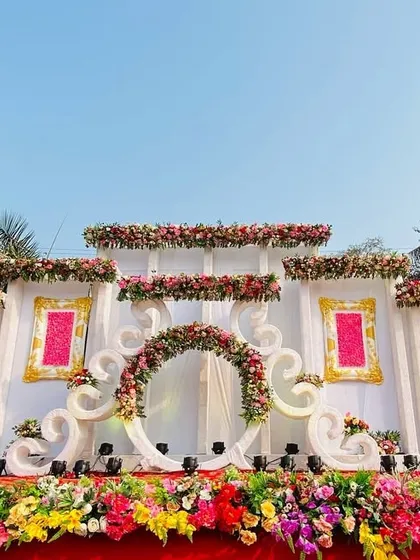 A beautiful and ornate stage in white, pink, and red. The design features multiple levels, decorative frames, and a central floral arch.