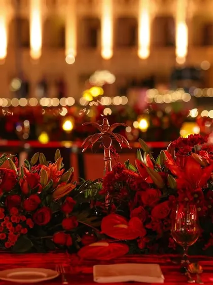 A close-up of the long floral runner on the dining table, with the blurred lights of the palace in the background creating a magical bokeh effect.