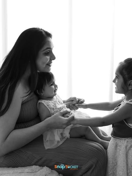 A timeless black and white portrait of a mother and her two daughters. This image focuses purely on the emotion and interaction between them, creating a classic piece of art.