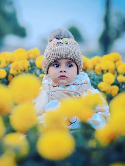 A beautiful baby boy portrait taken in a field of yellow marigolds. Using natural elements like flowers creates a stunning and vibrant backdrop for outdoor photoshoots.
