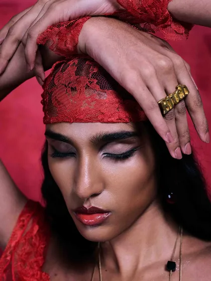 Published in Flanelle Magazine, this image uses a bold, monochromatic red theme. The focus is on the custom gold 'Brat' ring, with the model's pose and the lace headband adding layers of texture and attitude to this high-fashion accessory portrait.