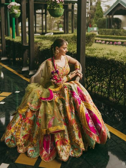 A full-length portrait of Vasav in her magnificent, multi-colored Haldi lehenga. She looks like a queen in her garden.