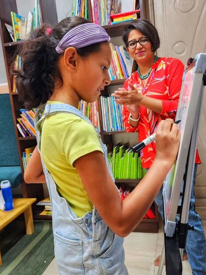 A young artist confidently takes to the whiteboard to share her doodle ideas with the class. We encourage every child to be brave, creative, and share their unique artistic voice.
