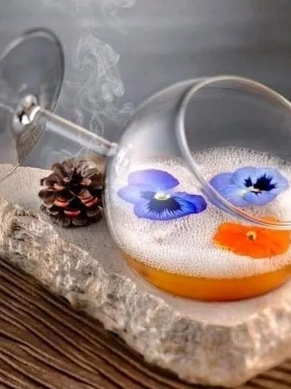 We believe in creative presentation for every drink. This unique cocktail is served in a tilted wine glass with edible flowers, creating a memorable and artistic visual for your guests.