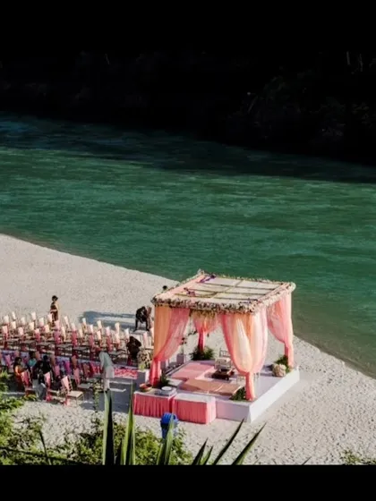 Another view of the riverside wedding setup in Rishikesh, showing the guest seating and the mandap against the stunning natural scenery.