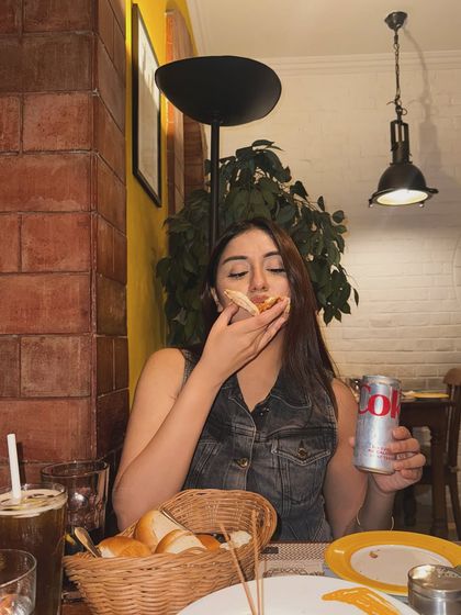 "3200 calories & a diet coke." A funny and relatable moment enjoying pizza at a restaurant in a denim vest.