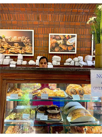 Peeking over the counter at a famous Auroville bakery, with trays of fresh pastries on display.