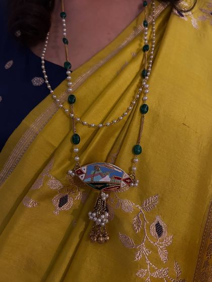 A close-up of a revived heirloom pendant. Our co-founder Nandini repurposed her nani's kamarband into this stunning pendant, pairing it with another heirloom mala for a look that is both unique and deeply personal.