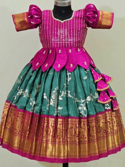 A beautiful combination of pink and teal green. This lehenga features a blouse with a petal-style peplum and a rich Banarasi silk skirt.