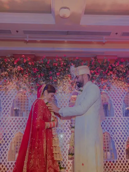 The groom places the garland on his bride, a simple, beautiful moment of acceptance and love, set against a stunning floral backdrop.