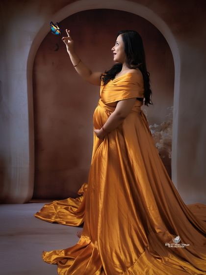A touch of magic in this solo portrait. The mom-to-be in a flowing yellow gown reaches out to a butterfly, creating a whimsical and hopeful image.