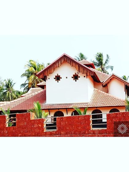 The Udupi house seen from behind its laterite stone compound wall. Laterite is a local stone, and using it for the boundary wall grounds the project in its specific regional context.