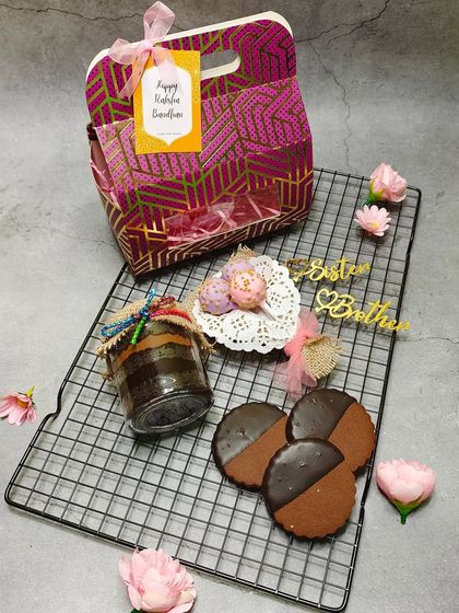 A dash of love and a basket full of surprises. This Rakhi gift bag includes a jar cake, cookies, and cake pops.