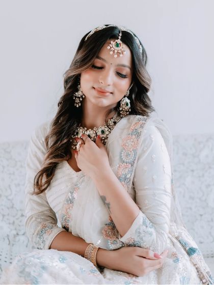 A close-up of the model looking down, showing the intricate details of the jewellery and the soft, romantic feel of the outfit.