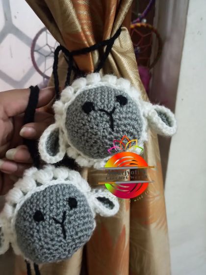 A pair of cute sheep curtain ties. These are perfect for a farm-animal-themed room or nursery and are made with soft, textured yarn to look like wool.