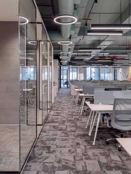 Glass-walled meeting rooms line the main corridor, reinforcing a culture of transparency. This design choice allows natural light to flow deep into the office floor plate while providing necessary acoustic privacy for meetings.