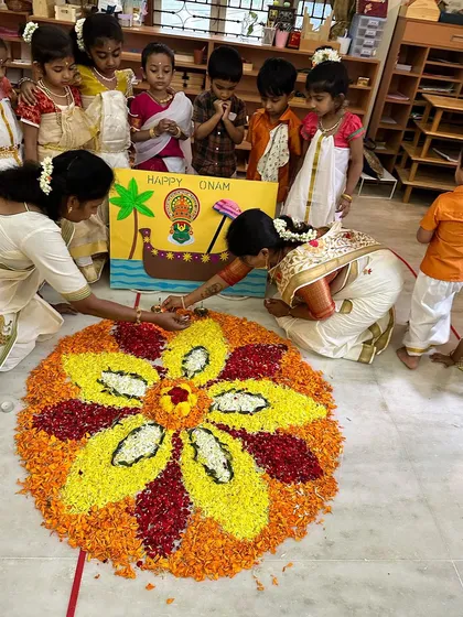 A teacher shows a child how to add the final touches to the pookalam, a moment of focused, shared creation.