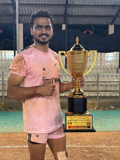 A player posing with his 'Best Player' trophy on the Kabaddi ground.
