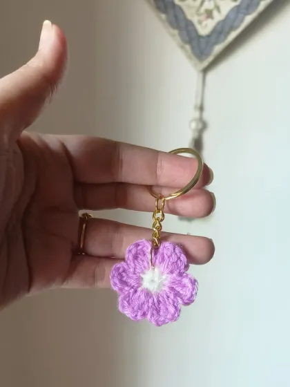 A single lilac floral keychain with a white center. The soft pastel color makes it a very sweet and gentle accessory.