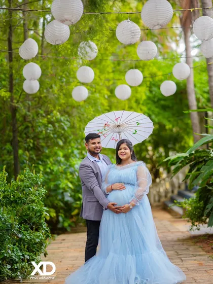 A romantic couple's portrait under hanging white lanterns in a beautiful garden path.