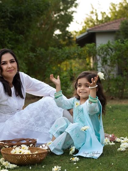 A quiet moment on the grass, surrounded by flowers. This mother and daughter portrait captures the gentle and loving bond they share during a relaxed outdoor brand shoot.