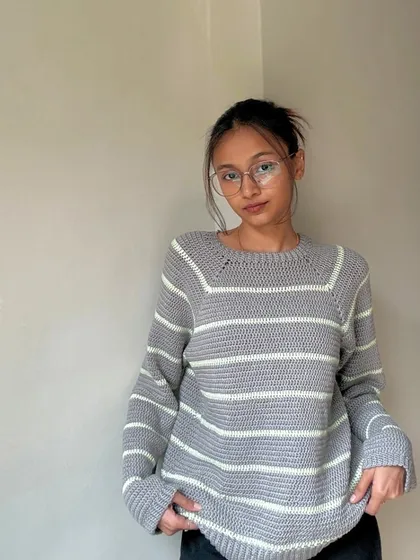 The final look of the grey and mint striped sweater. It has a relaxed fit and is made from a soft, warm acrylic yarn.