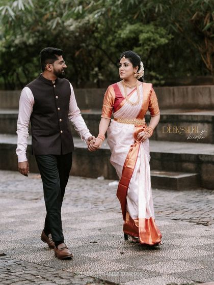 A classic walking shot of the couple, hand in hand. The bride in her traditional saree and the groom in his smart attire make a picture-perfect pair.