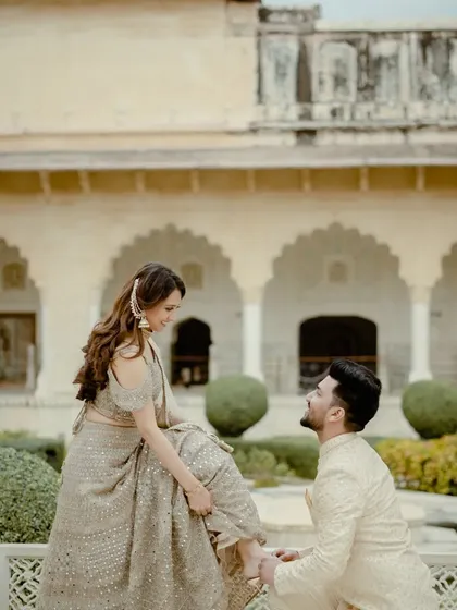 A classic, chivalrous moment in the gardens of a Jaipur palace. This pose is timeless and romantic, perfectly fitting the royal theme of the location.