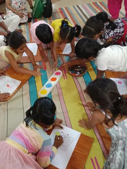 Children lie on the floor to color their butterfly pictures, showing the relaxed and informal vibe of our sessions.