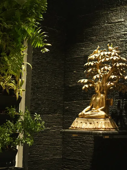 This composition shows a golden Buddha statue on a shelf, thoughtfully placed next to a living wall, creating a harmonious blend of spiritual art and natural beauty.