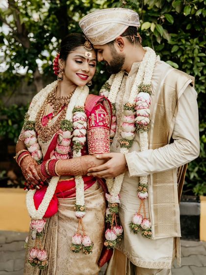 A tender embrace between the newly married couple, showcasing their beautiful traditional outfits and garlands.