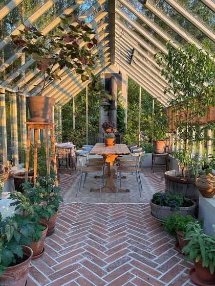 A beautiful greenhouse designed as a multi-purpose living space. With brick flooring and ample room for a dining table, it serves as a protected, light-filled room to enjoy the garden in any weather.