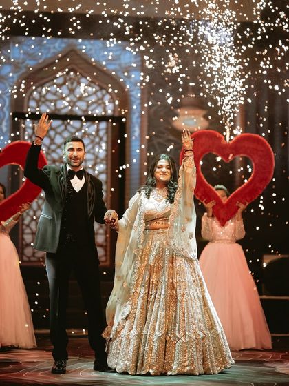 A grand finale moment. The couple waves to their guests, framed by giant hearts and a shower of sparklers, a perfect, high-energy end to their ring ceremony performance.