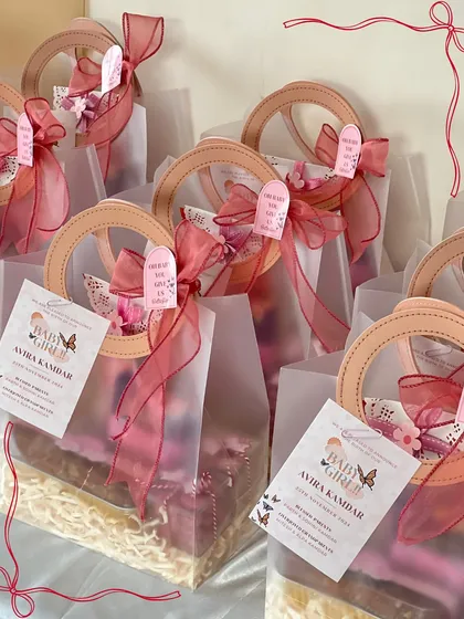 These elegant semi-transparent bags with ring handles were perfect for the baby girl announcement gifts. Each one is tied with a ribbon and a custom tag.