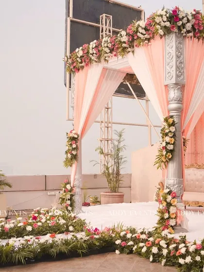 A side angle of the peach and white floral mandap, showing how the design harmonizes with the open-air venue for a light and airy feel.