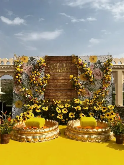 Another angle of the stunning rooftop Haldi stage, showing the beautiful contrast between the yellow decor, the historic building, and the clear blue sky.