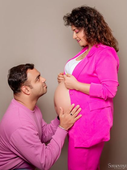 A sweet and adoring moment as the father-to-be looks up at his partner and their baby bump. A modern take on a classic pose.