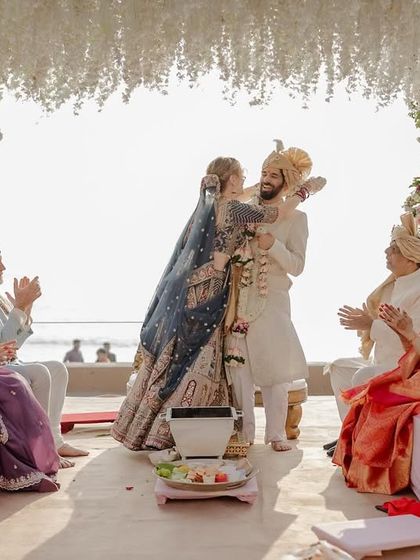 A wide shot of the beach wedding ceremony, capturing the joy of the guests and the beautiful setting.