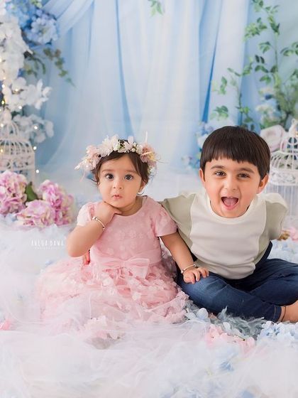 A duplicate of image 81, capturing a fun and silly moment between siblings in a floral wonderland setting.