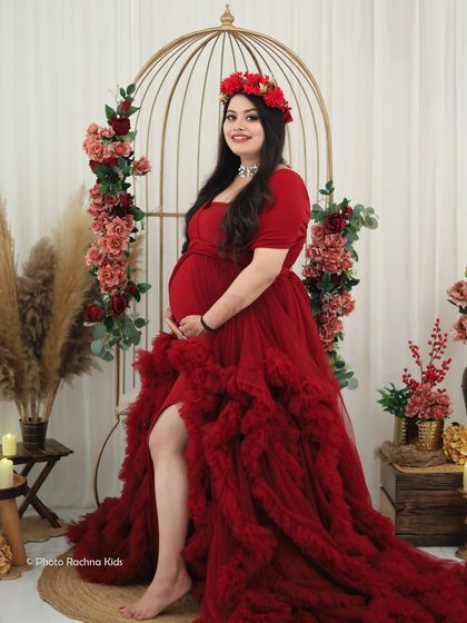 A solo portrait that radiates confidence and joy. The combination of a bold red gown, a floral crown, and our elegant studio set makes for a truly memorable photo.