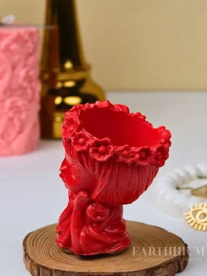 A detailed look at the red figurine holder, showing its form before it's used as a vase or candle holder. The floral crown detail is one of my favorite parts.