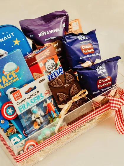 A closer look at the contents of our space-themed hamper, featuring an Avengers keychain, Hello Panda biscuits, and an Oreo chocolate bark, all packed in a clear acrylic tray.